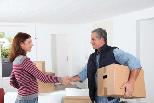 Removalists carrying furniture from a Barking flat with stair access